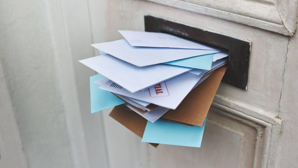 A stack of documents that can be used as proof of address online hanging out from the letterbox.
