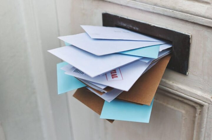 A stack of documents that can be used as proof of address online hanging out from the letterbox.